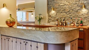 A bar area with a stone wall backdrop, a marble countertop, and various bottles and glasses. - Best Western Plus Pays du Mont Blanc (Passy)