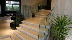 Una escalera moderna con barandales de vidrio y una planta en maceta a su lado.