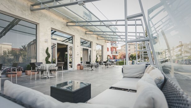 Un área de patio al aire libre con mobiliario, techo de vidrio y vista a la ciudad.