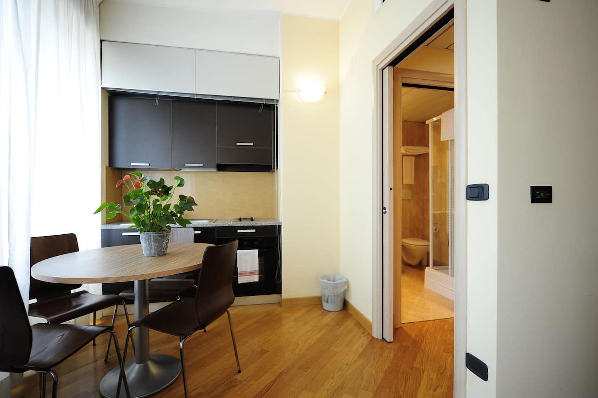 A modern kitchen with dark cabinets, a round dining table, and a potted plant.