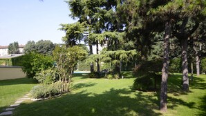 A well-maintained garden with a variety of trees and shrubs, a clear pathway, and a building in the background. - Corvetto Residence (Milan)