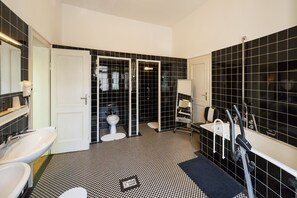 A modern bathroom with a black and white checkered floor, a white sink, a toilet, and a shower area.