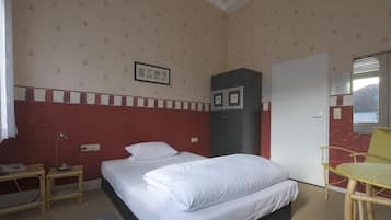 Ein Schlafzimmer mit Bett, Kleiderschrank, Schreibtisch mit Lampe und Stuhl.