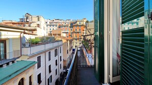 Una calle urbana estrecha con edificios a ambos lados, una reja metálica y un cielo azul despejado.