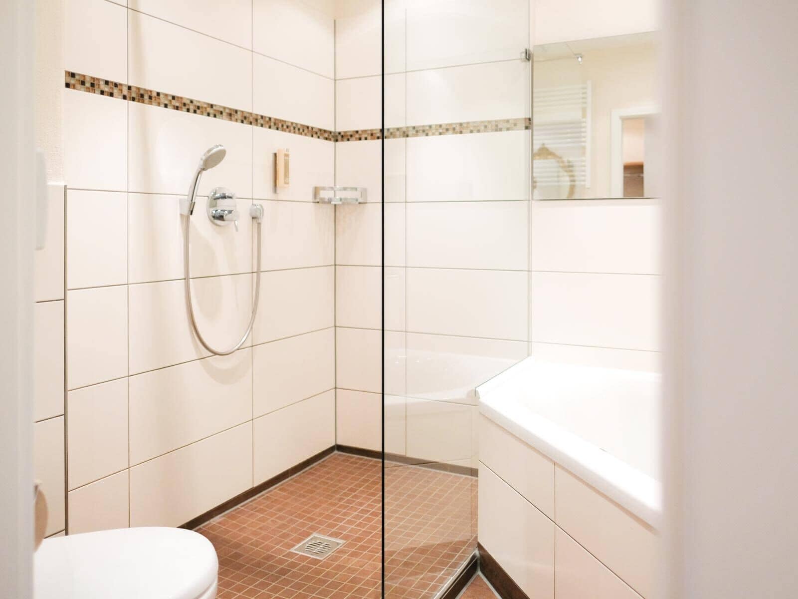 Un baño moderno con cabina de ducha de vidrio, inodoro blanco y bañera.