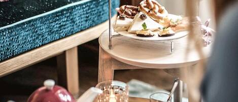 A tiered dessert stand with various pastries and a tea set on a table.