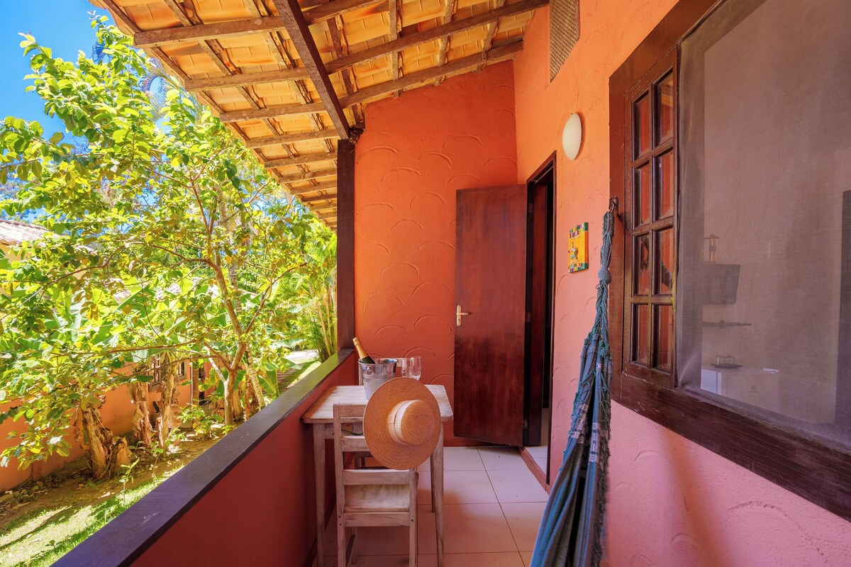 Een balkon met een houten tafel, stoelen en een hoed.
