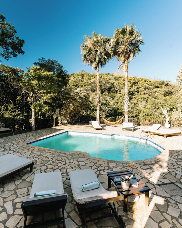 Una piscina al aire libre, sombrillas, sillones reclinables de piscina