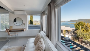 Un salon moderne avec un canapé blanc, un miroir rond et une vue sur la mer.