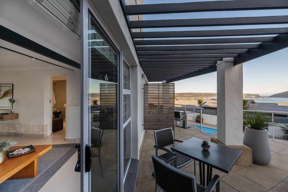 Une terrasse extérieure moderne, dotée d’une piscine, de coins salon et offrant une vue sur le paysage.