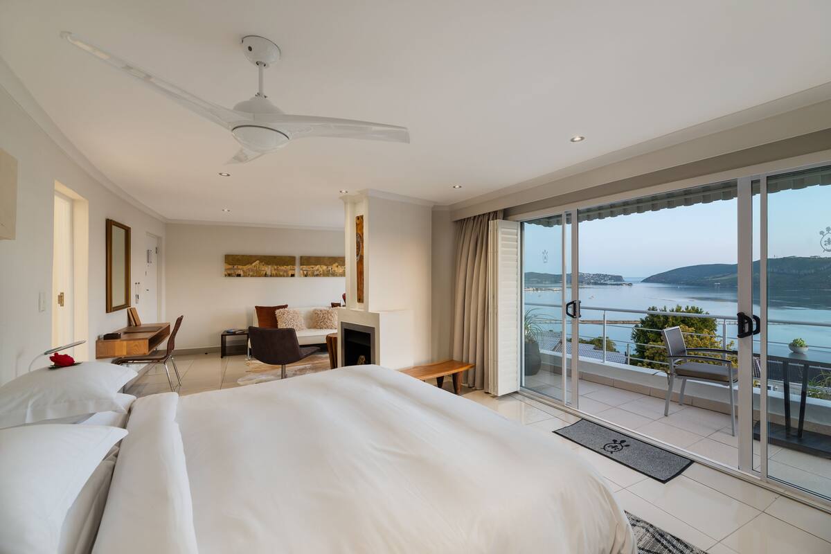 Une chambre d’hôtel avec un grand lit, un bureau, une chaise et un balcon donnant sur la mer.