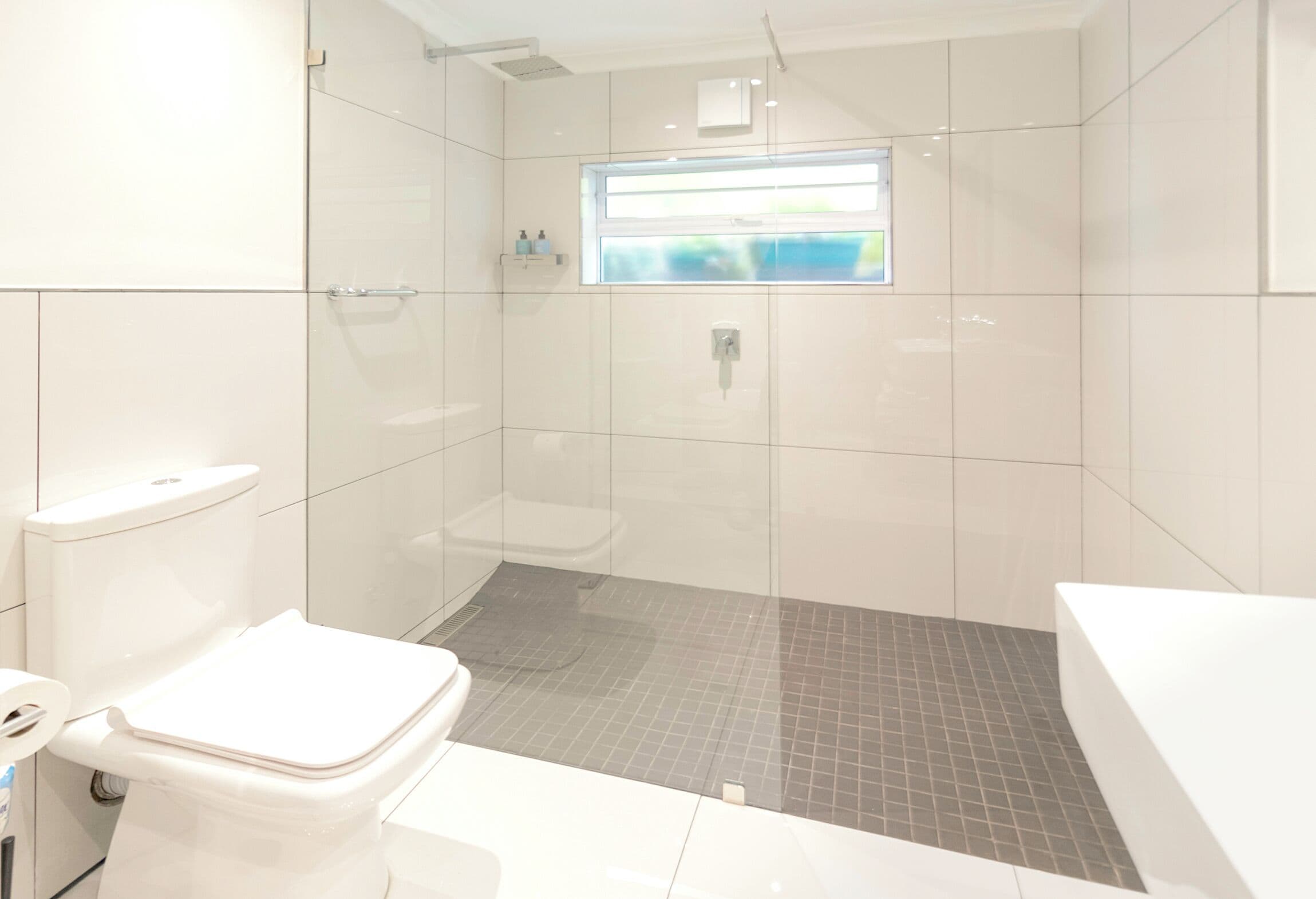 A modern bathroom with a toilet, shower, and sink.