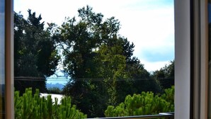 A balcony with a glass table and chairs, overlooking a garden and a body of water. - Hellinis Hotel (Corfu)