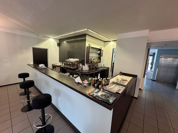 A modern bar area with a coffee machine, bar stools, and a magazine rack.