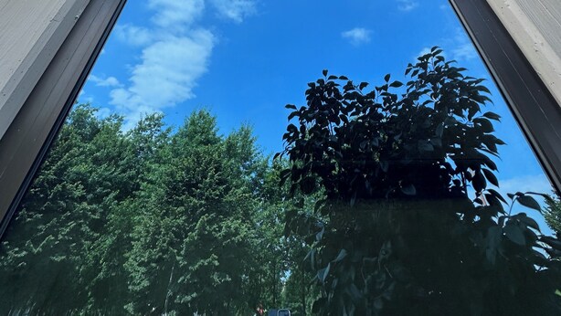 Een modern gebouw met grote glasramen en vrij uitzicht op de lucht en bomen.