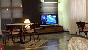 Una sala de estar con televisor, una mesa de comedor y sillas.