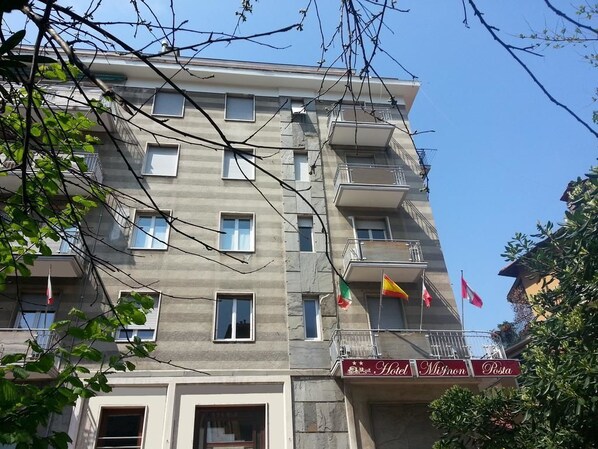 Un hôtel à plusieurs étages, doté de balcons et de drapeaux.