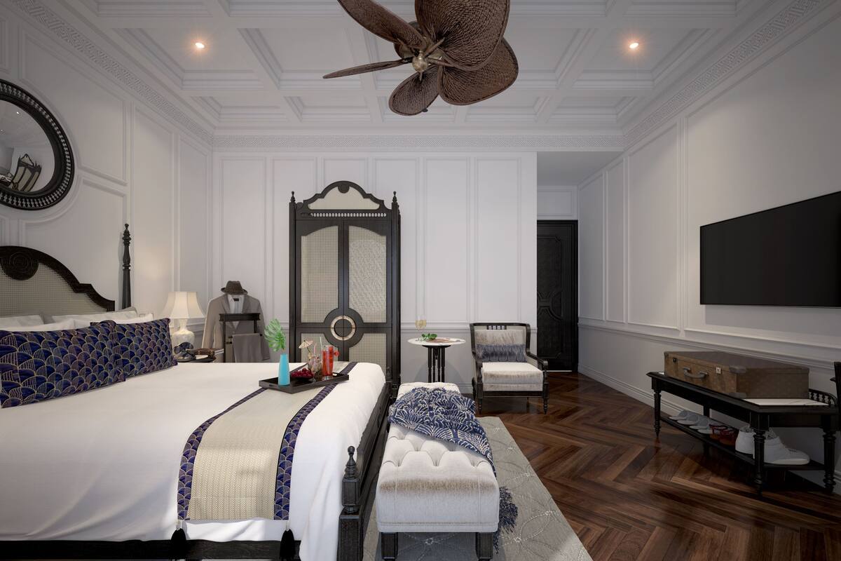 A hotel room with two beds, a large ceiling fan, a TV, a small table, and a chair.