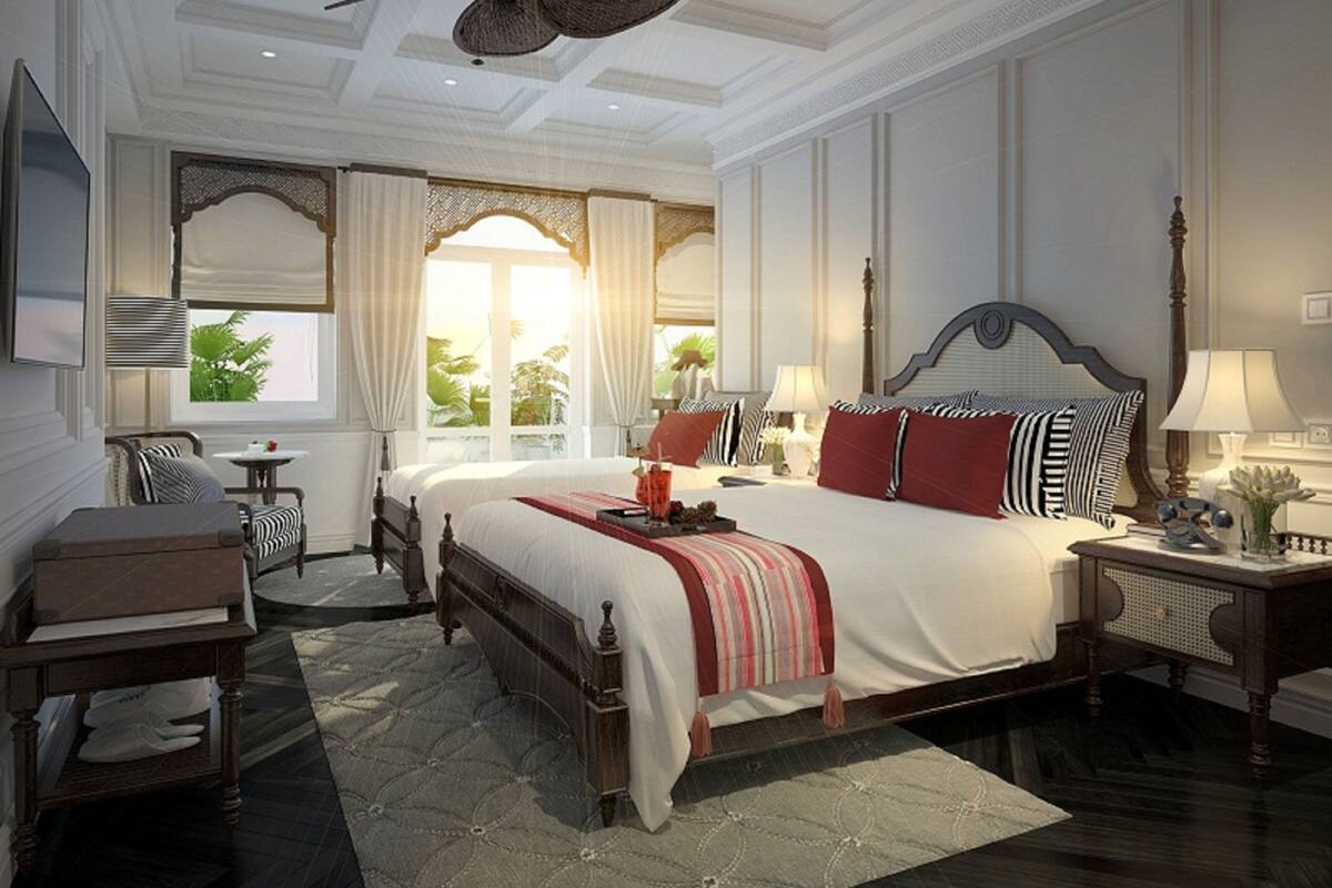 A spacious bedroom with a large bed, a sitting area with a chair and table, and a window with curtains.