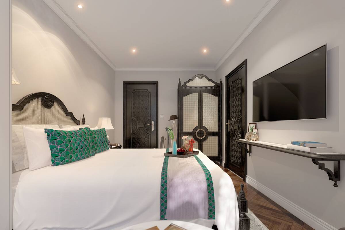 A hotel room with a large bed, a TV mounted on the wall, and a door with intricate designs.