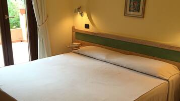 Et hotelværelse med en seng, et natbord, en lampe og et billede på væggen.