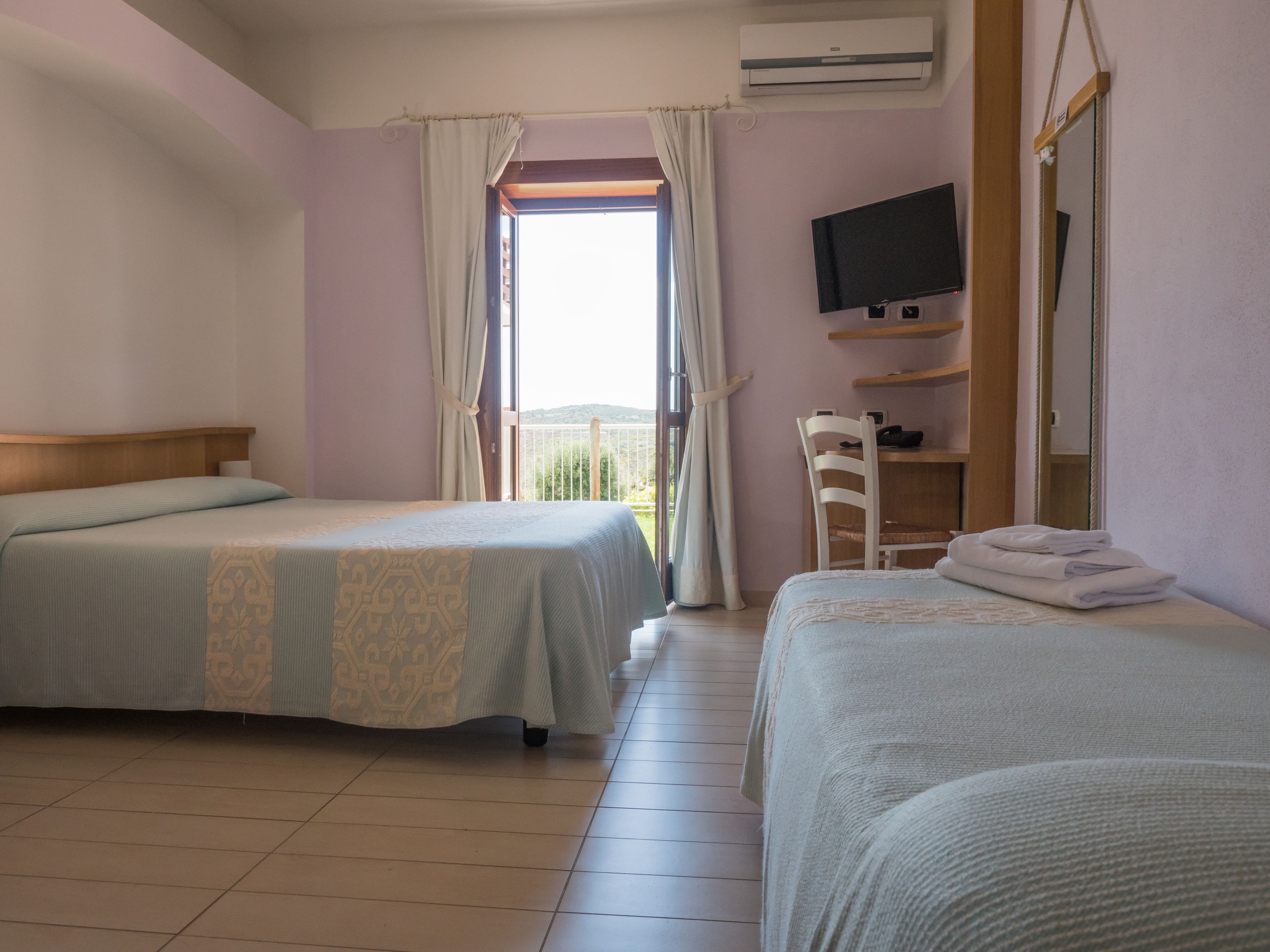Une chambre d’hôtel avec deux lits, une télévision, un bureau et un balcon avec vue.