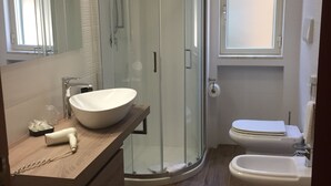 A modern bathroom with a glass shower enclosure, a large sink, and a toilet. - Casa Famiani Bed & Breakfast (Letojanni)