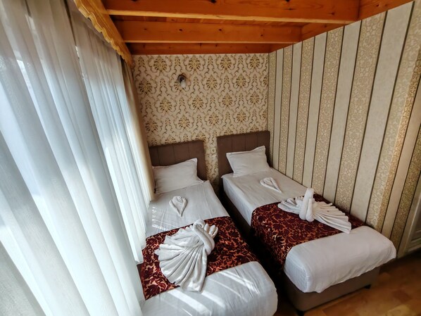A hotel room with two beds, each with a neatly folded towel and a patterned bedspread. - Sirkeci Emek Hotel (Istanbul)