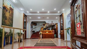 A hotel lobby with a reception desk, a staircase with red carpet, and a large painting on the wall. - Sirkeci Emek Hotel (Istanbul)