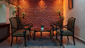 A room with a brick wall, four upholstered chairs, a round table, and a patterned rug. - Sirkeci Emek Hotel (Istanbul)