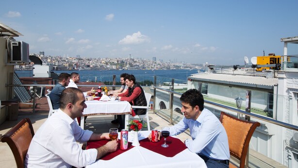 A rooftop dining area with tables set for four, overlooking a cityscape and the sea. - Sirkeci Emek Hotel (Istanbul)
