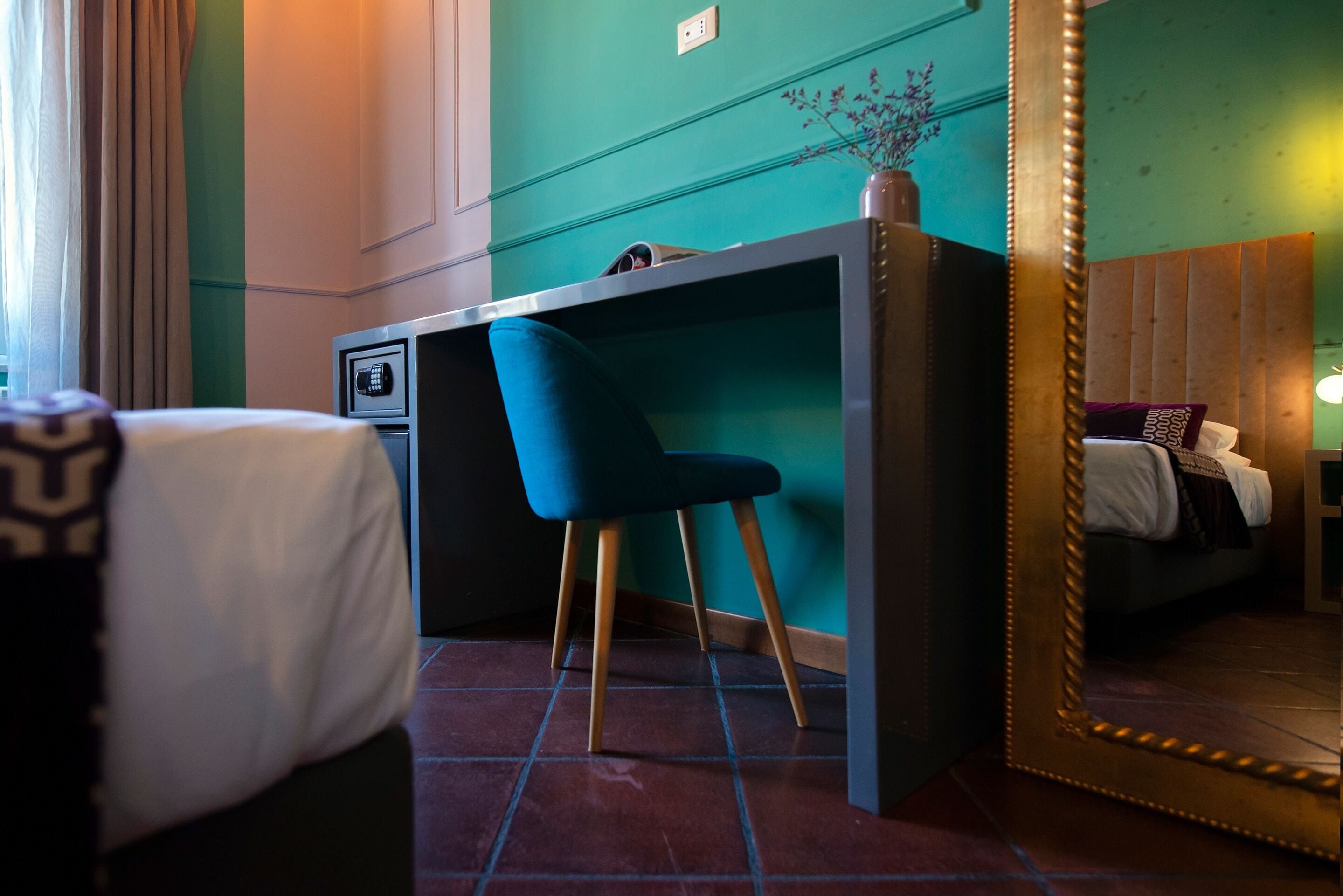 A hotel room with a bed, a desk, a chair, and a large mirror.