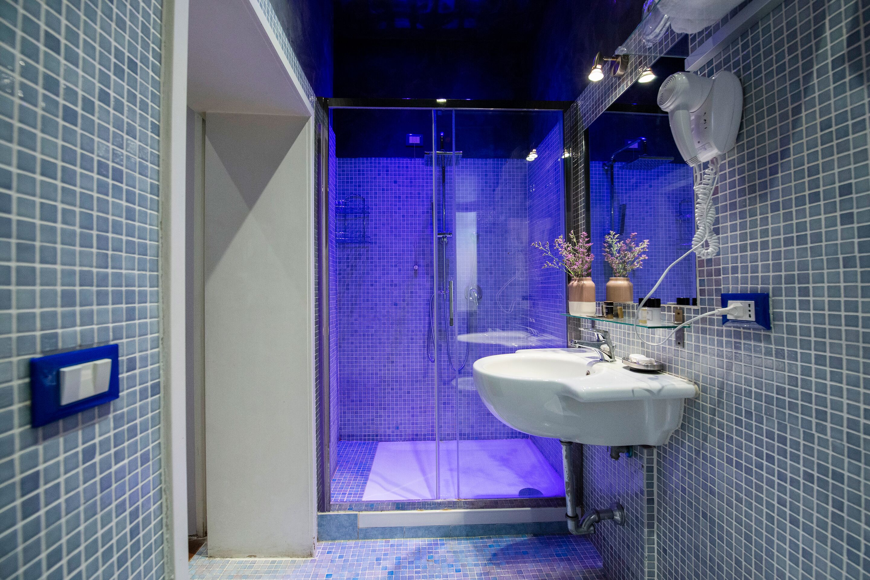 Um banheiro moderno com box de vidro, pia branca e parede com azulejos azuis.