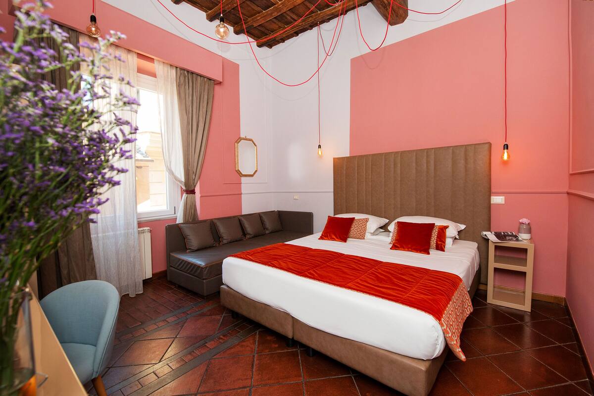 A bedroom with a large bed, a sofa, a chair, and a nightstand.