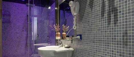 A bathroom with a bidet, a glass-enclosed shower, and a tiled floor.