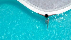 Una persona nada en una piscina azul cristalina con un borde de baldosas.