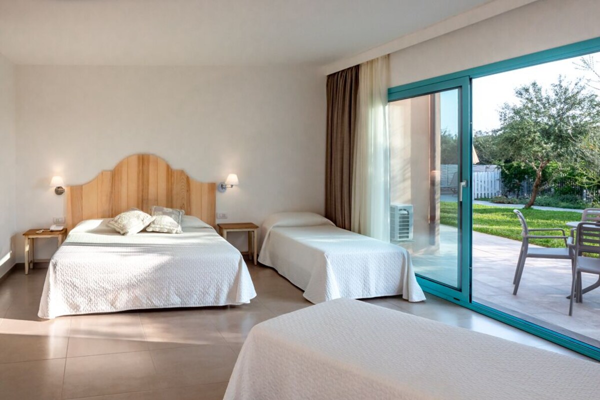 Habitación de hotel con dos camas, un ventanal grande y vistas al exterior.