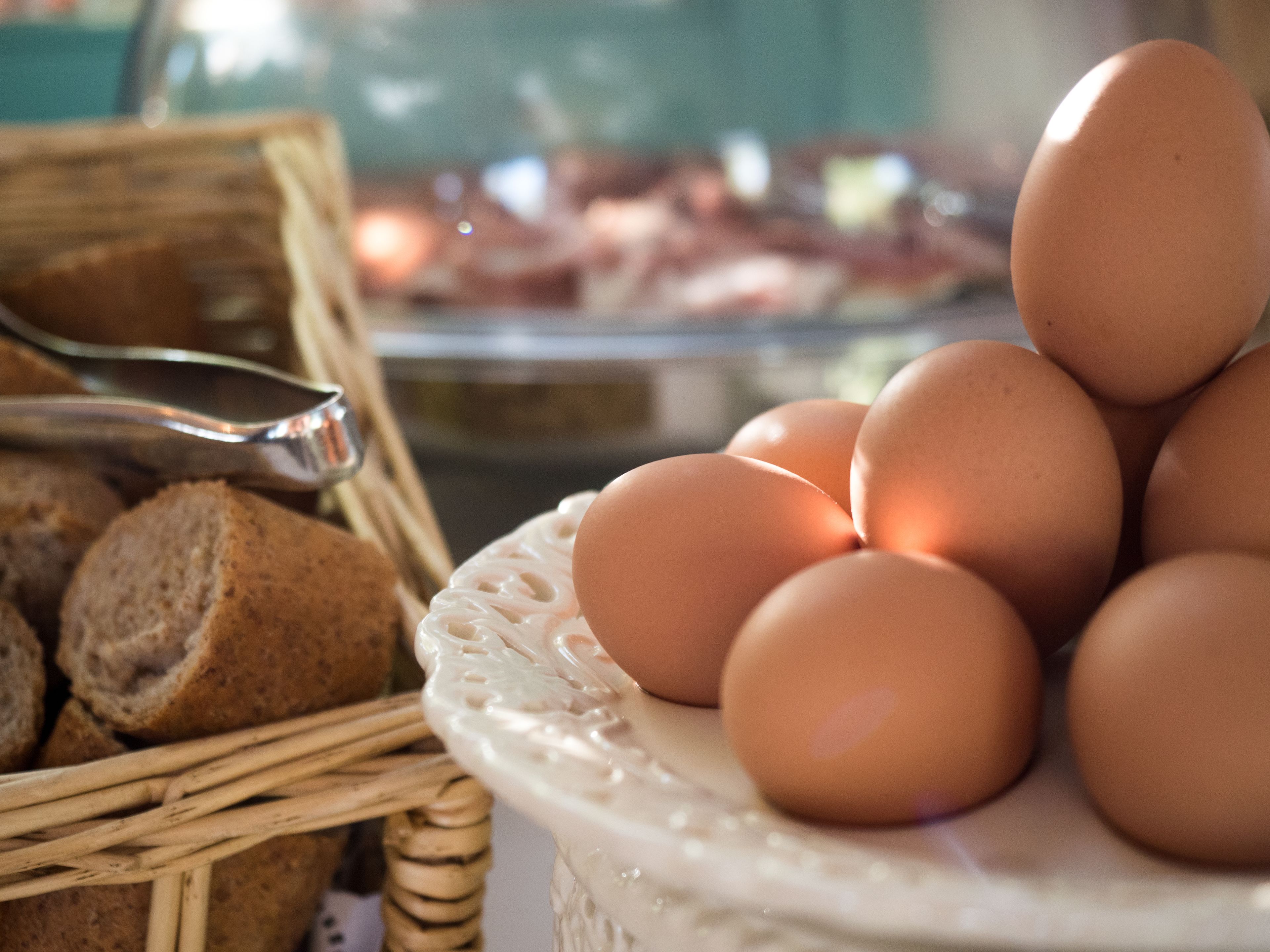 A wicker basket with bread and a plate of eggs.