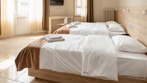 Habitación de hotel con dos camas, cabecero de madera, televisor de pantalla plana, escritorio y ventana con cortinas.