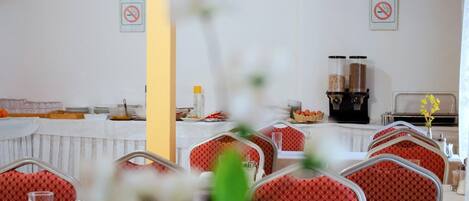 A dining area with tables set for service, a buffet line, and a coffee station.