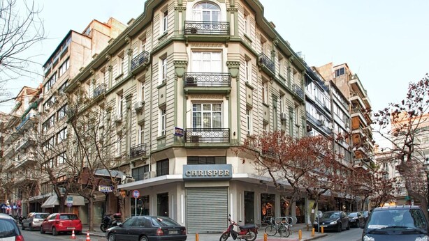 Un edificio en esquina con un letrero que dice "CHRISTER", varios balcones y un letrero que indica "HOTEL".