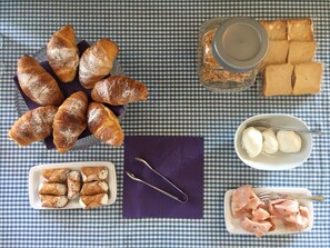 A table with croissants, bread, a bowl of cheese, and a glass of water. - OrtigiaSeaView Bed & Breakfast (Syracuse)