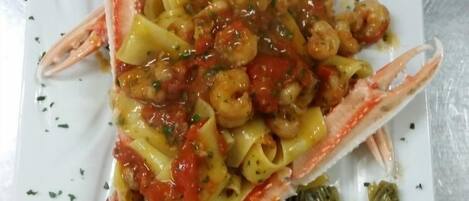 A seafood dish with pasta and vegetables on a white plate.