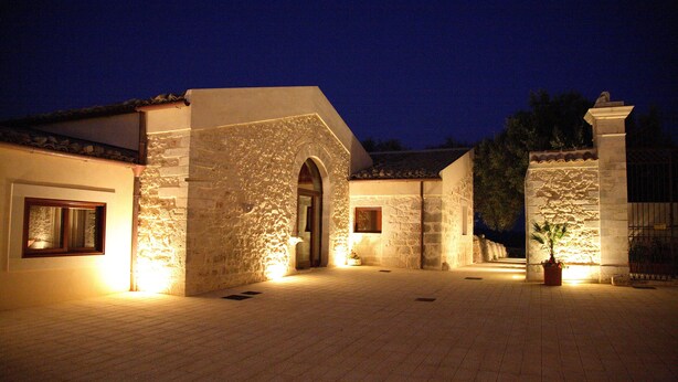 Un edificio de piedra con una entrada abovedada, iluminado por luces interiores.