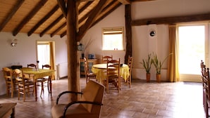 Un coin repas avec des meubles en bois, un sol carrelé et une fenêtre avec des rideaux.