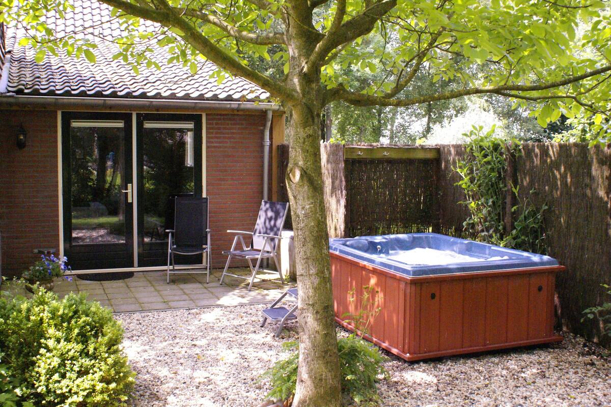 A backyard with a hot tub, a patio chair, and a wooden fence.
