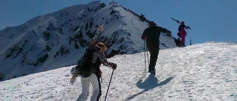 A snowy mountain landscape with two people hiking.