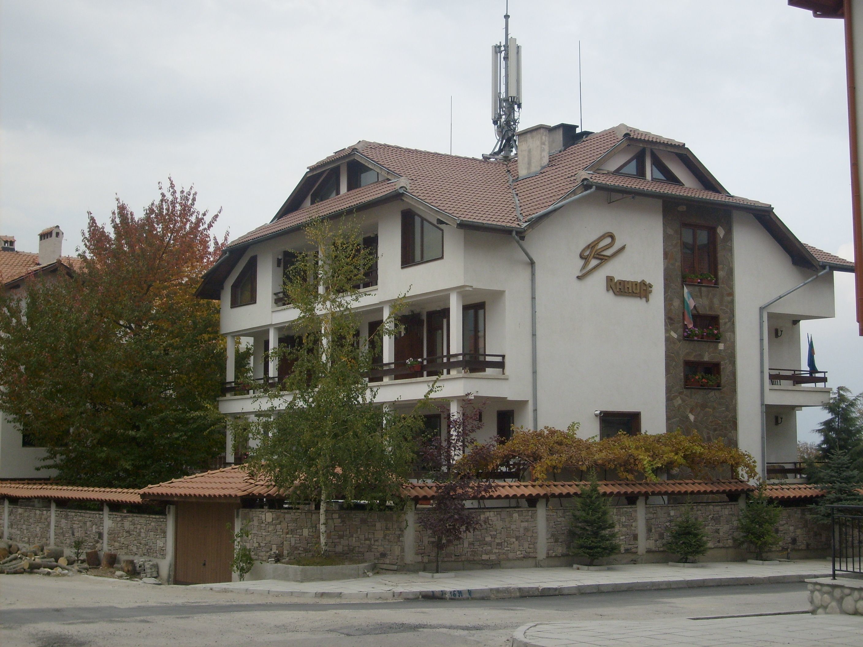 Un edificio de dos pisos con fachada de piedra, varios balcones y un letrero con un logotipo.