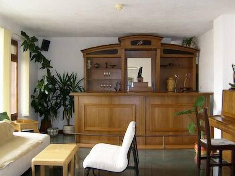 Una sala de estar con un mueble de madera, una silla blanca, una mesa de madera y un sofá.