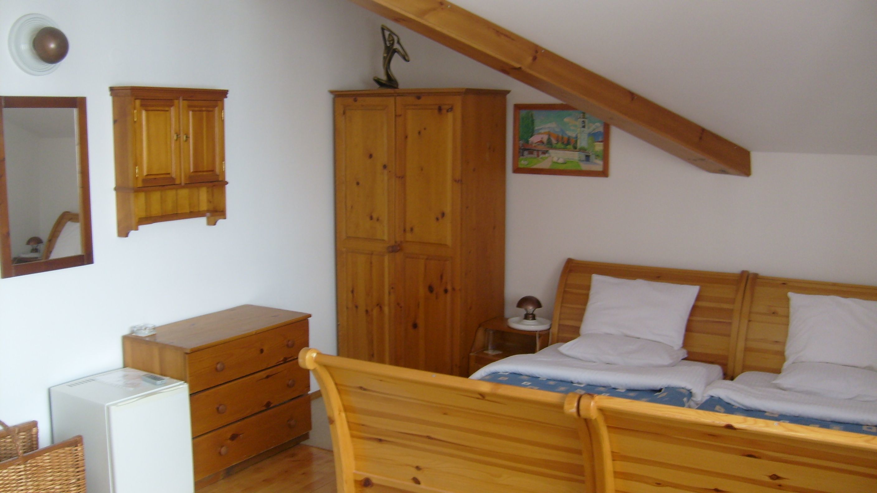 Una camera da letto con un letto e un comò in legno, un armadio, un comodino con una lampada e un quadro appeso al muro.